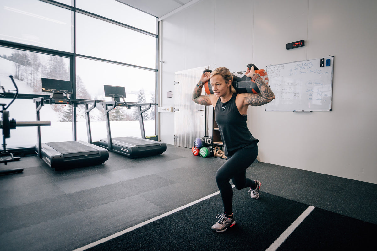 Frau führt Lunges mit Atletica Power Bag im Fitnessstudio aus