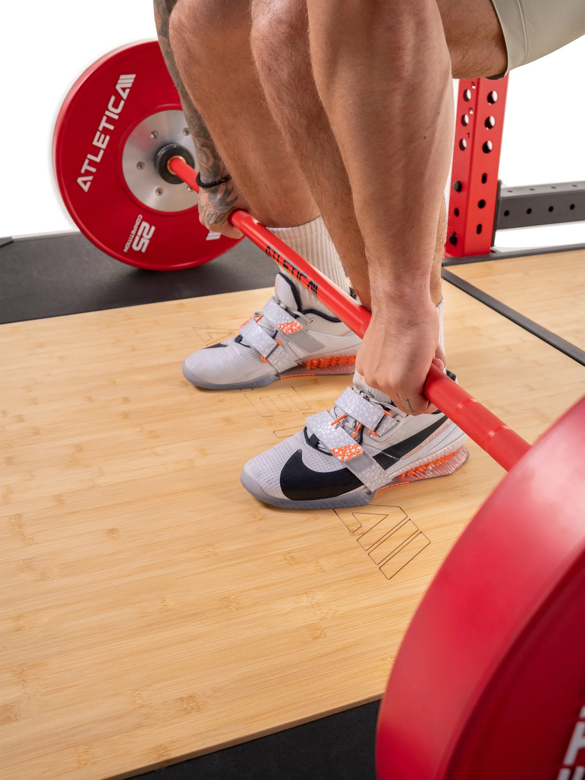 Feet in lifting shoes on the bamboo surface of the Atletica deadlift platform, close-up