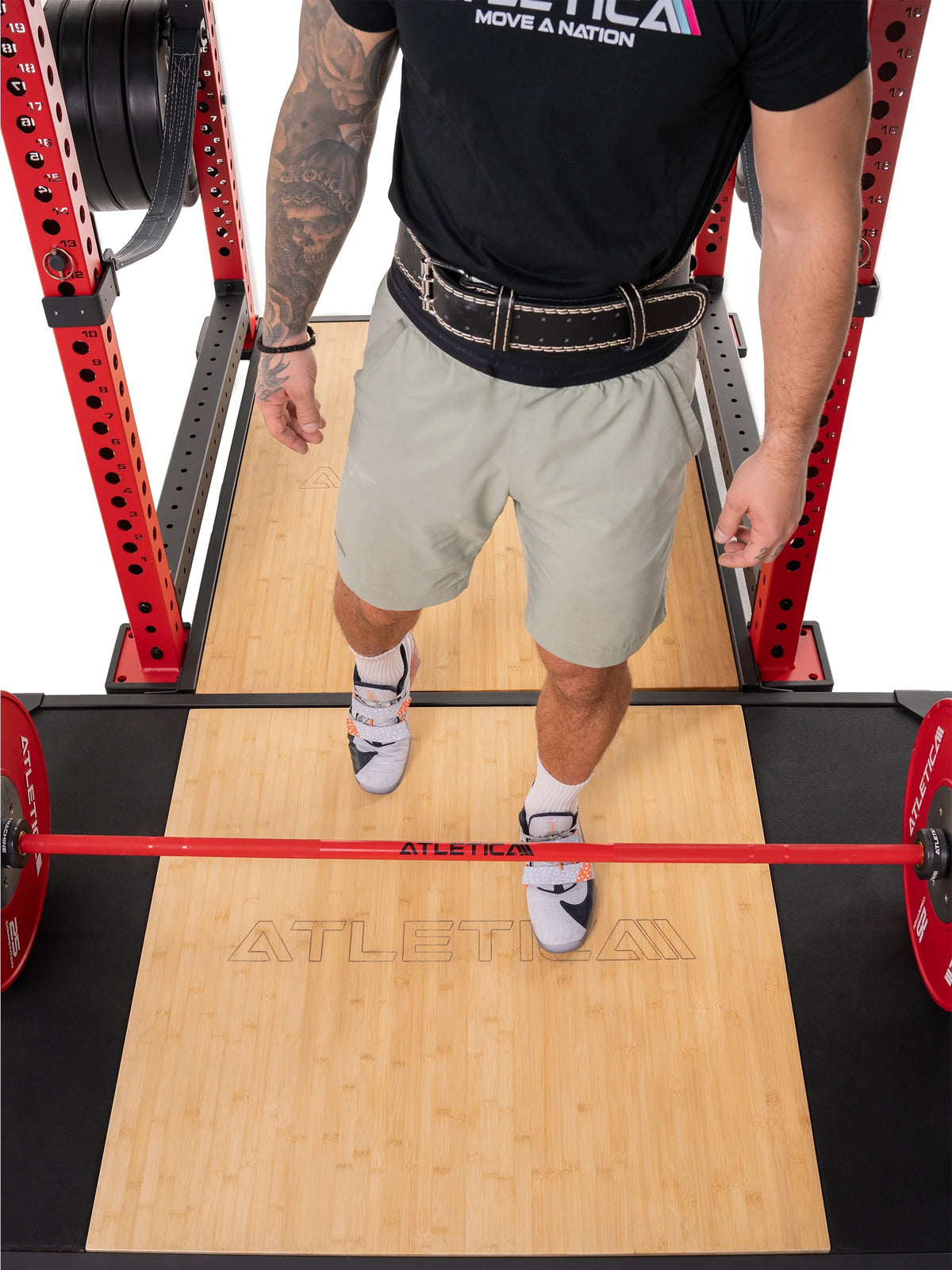Man standing on the bamboo center of the Atletica deadlift platform in a power rack