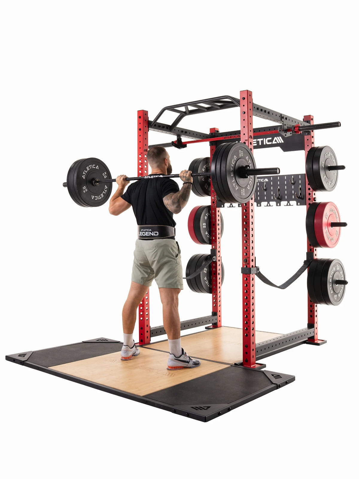 Man doing back squats on the Atletica T-shape deadlift platform with red power rack