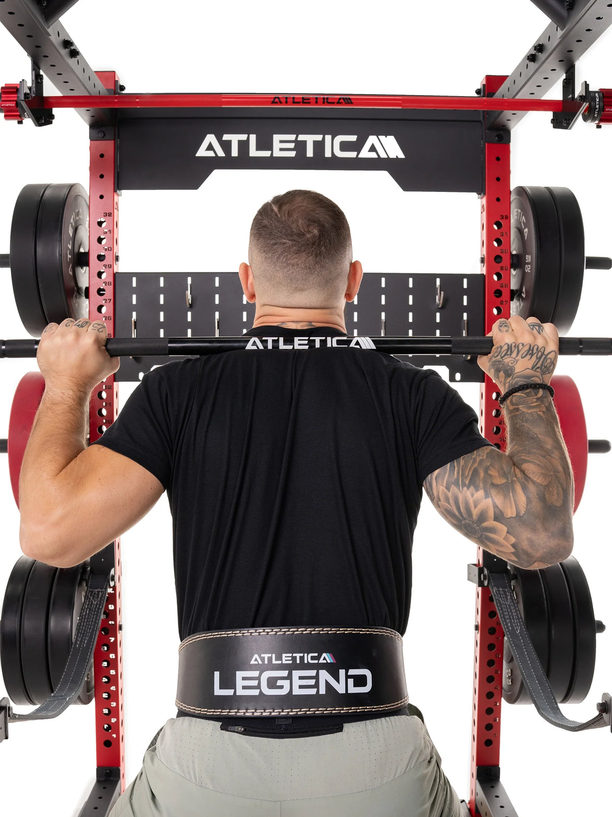 Man in a lifting belt doing front rack squats on the Atletica deadlift platform, rear view