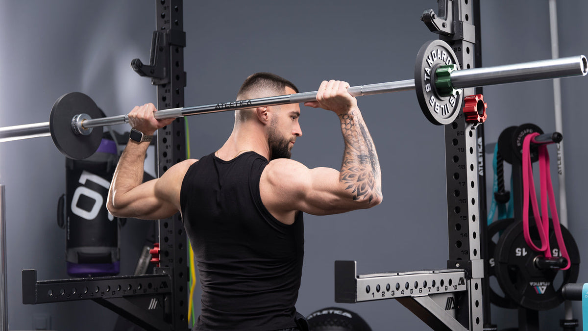 Shoulder training with an Atletica barbell and Iron Plates in the gym