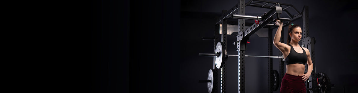 Woman doing a single-arm overhead press with an Atletica lever arm attachment on a R8 power rack