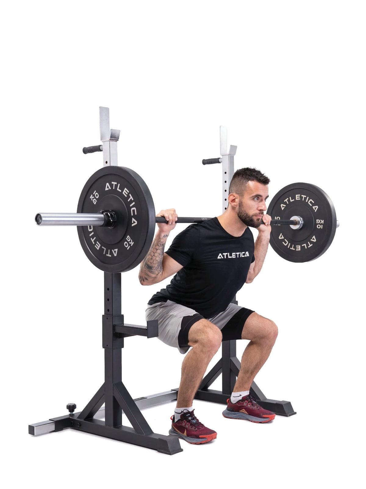 Man doing barbell back squats with the Atletica free-standing squat stands and Gamma barbell