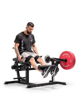 Athlete doing leg extensions on the Atletica Leg & Core Multi-Trainer with a red weight plate