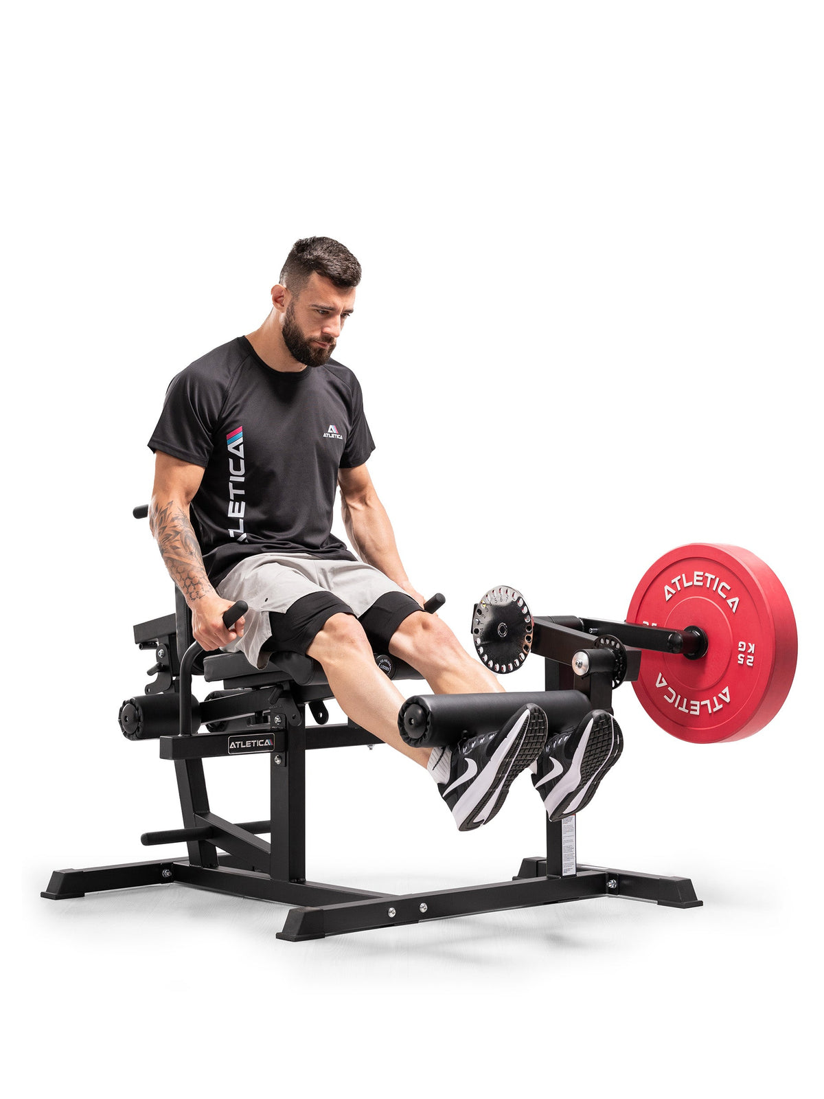 Athlete doing leg extensions on the Atletica Leg & Core Multi-Trainer with a red weight plate