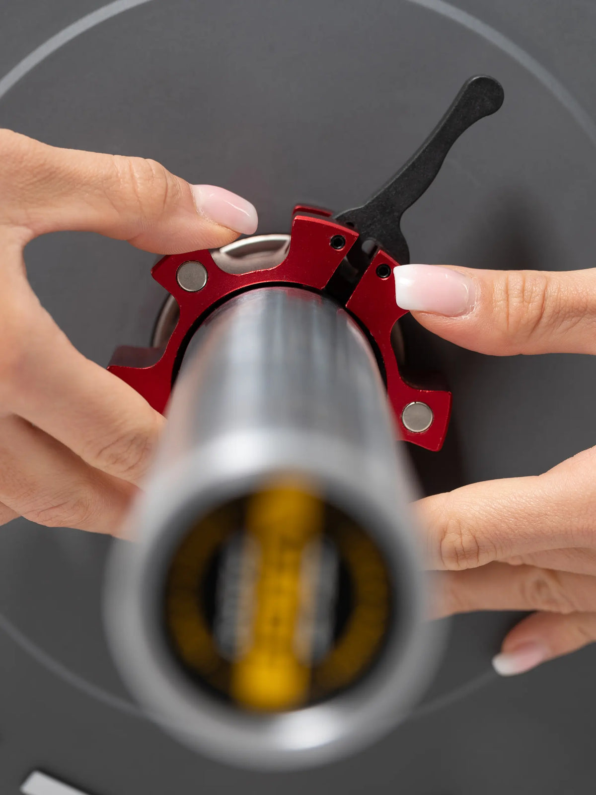 Hands sliding a red Atletica aluminum barbell collar onto a barbell, front view