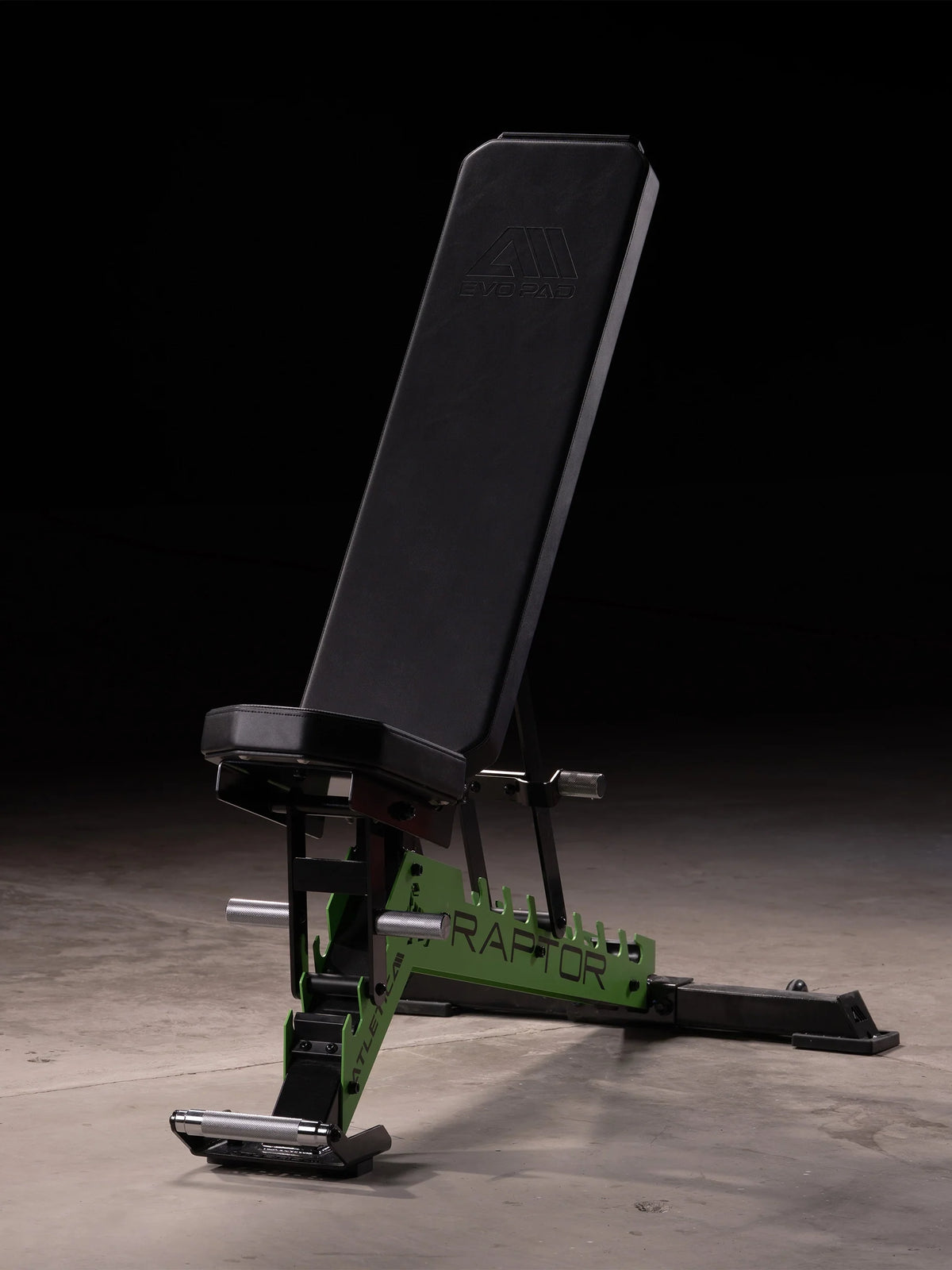Atletica Raptor adjustable weight bench with green frame in upright position in a dark gym