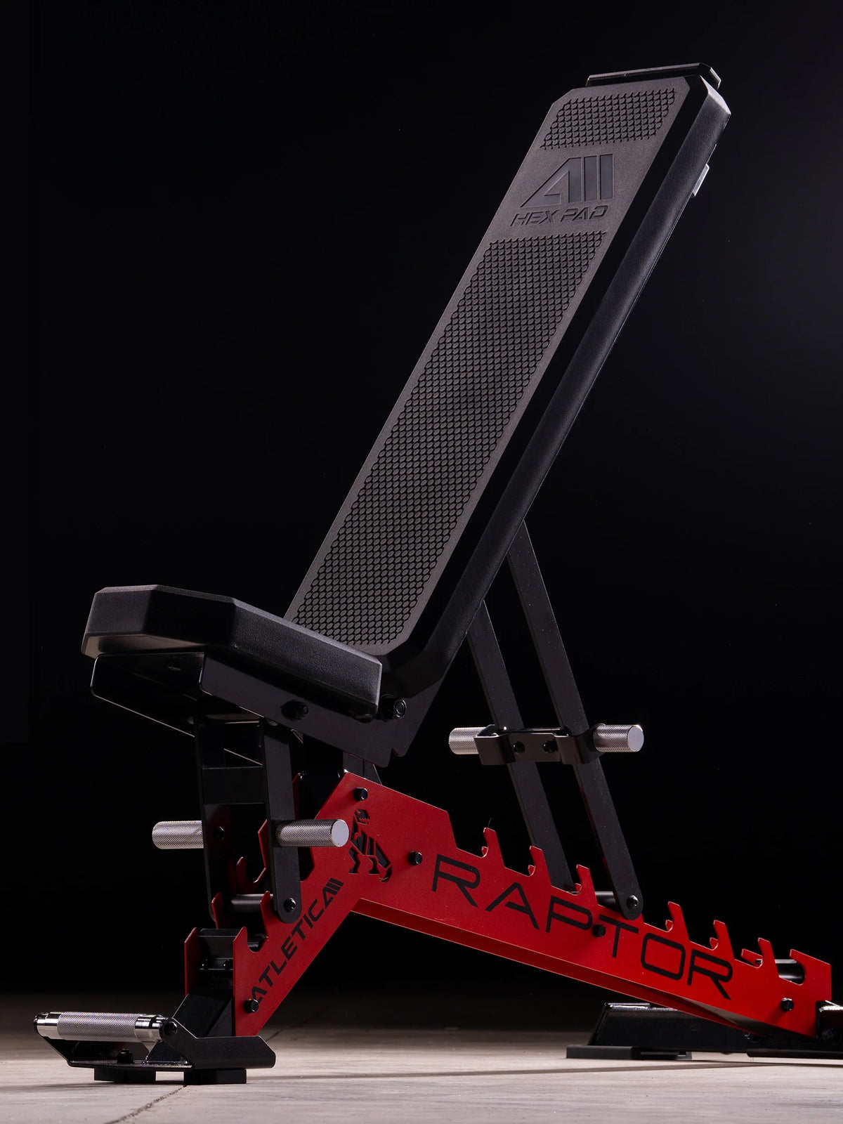 Atletica Raptor adjustable weight bench with red frame, angled front view on a dark background