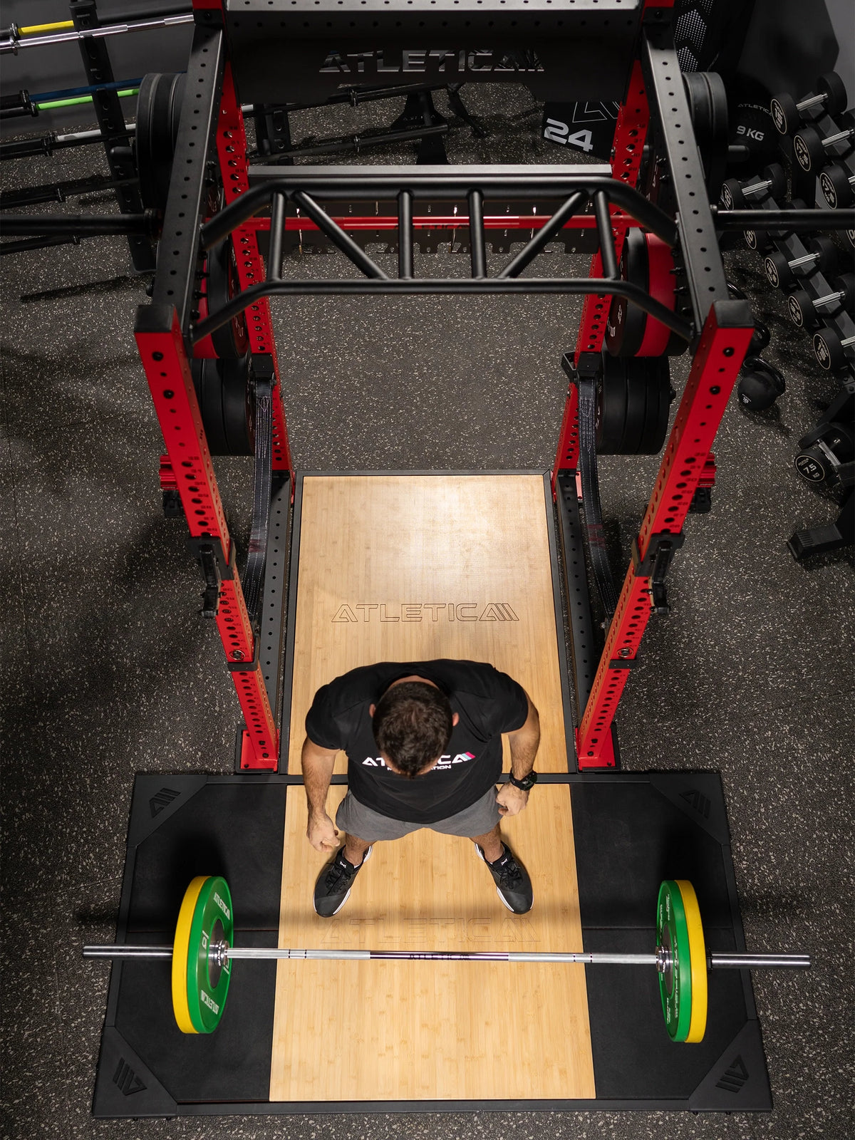 Man doing deadlifts on the Atletica T-shape deadlift platform inside a power rack, top view