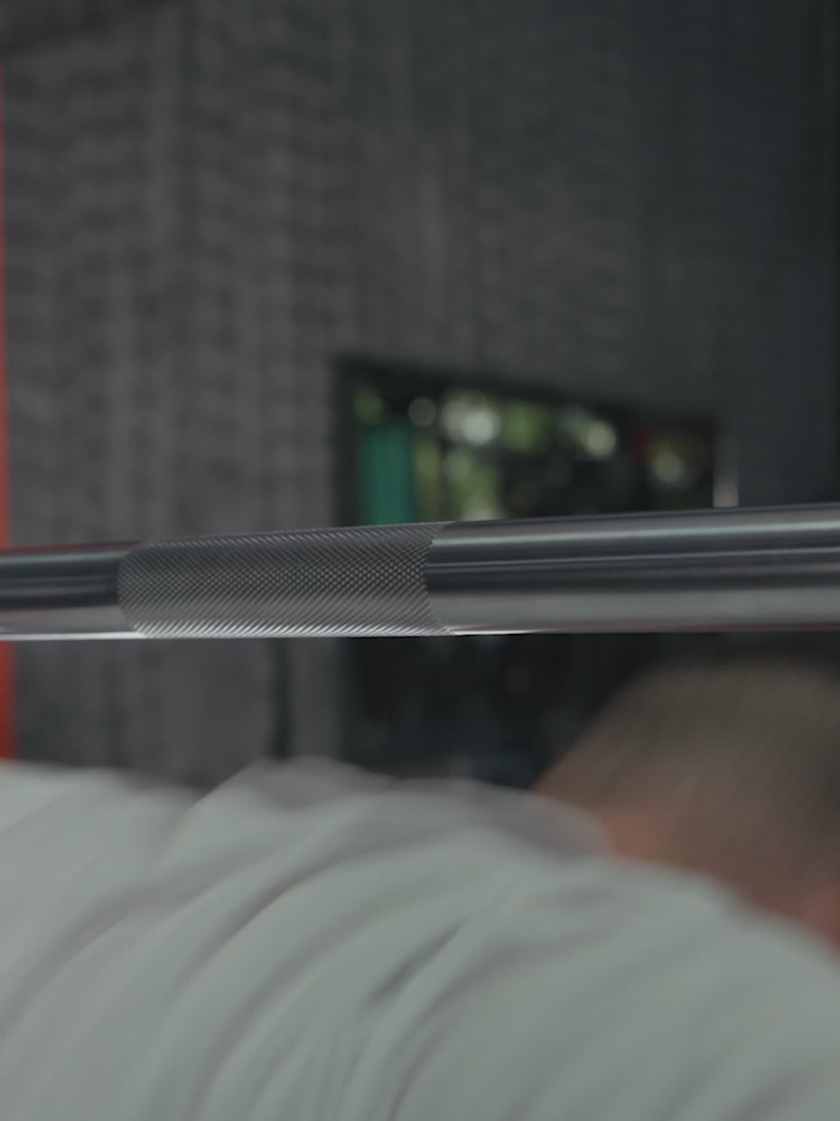 Video: Atletica Beta powerlifting bar in chrome, close-up of the knurled bar above a lifter