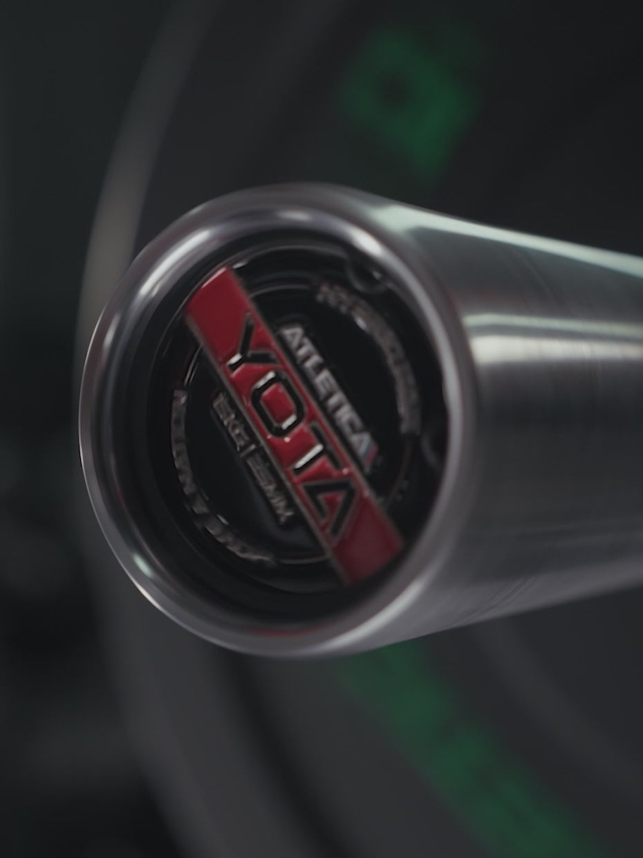 Woman doing bench presses with the Atletica Yota barbell, close-up of the red end cap